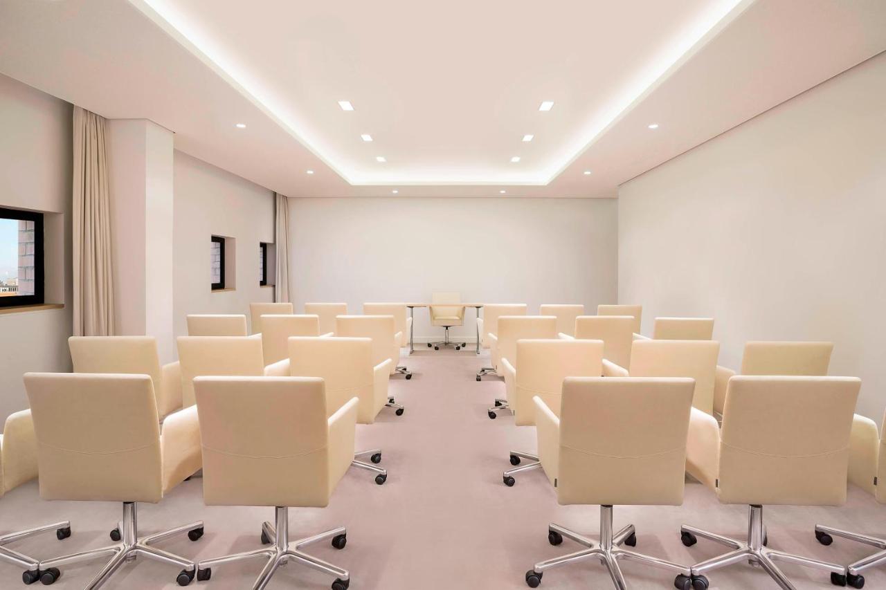 מלון The Westin Hamburg Elbphilharmonie מראה חיצוני תמונה The photo shows a modern conference room. There are several light-colored, wheeled chairs arranged in rows facing a central area where a glass table is located. The room has soft lighting from recessed ceiling lights, and the walls are mostly white, 