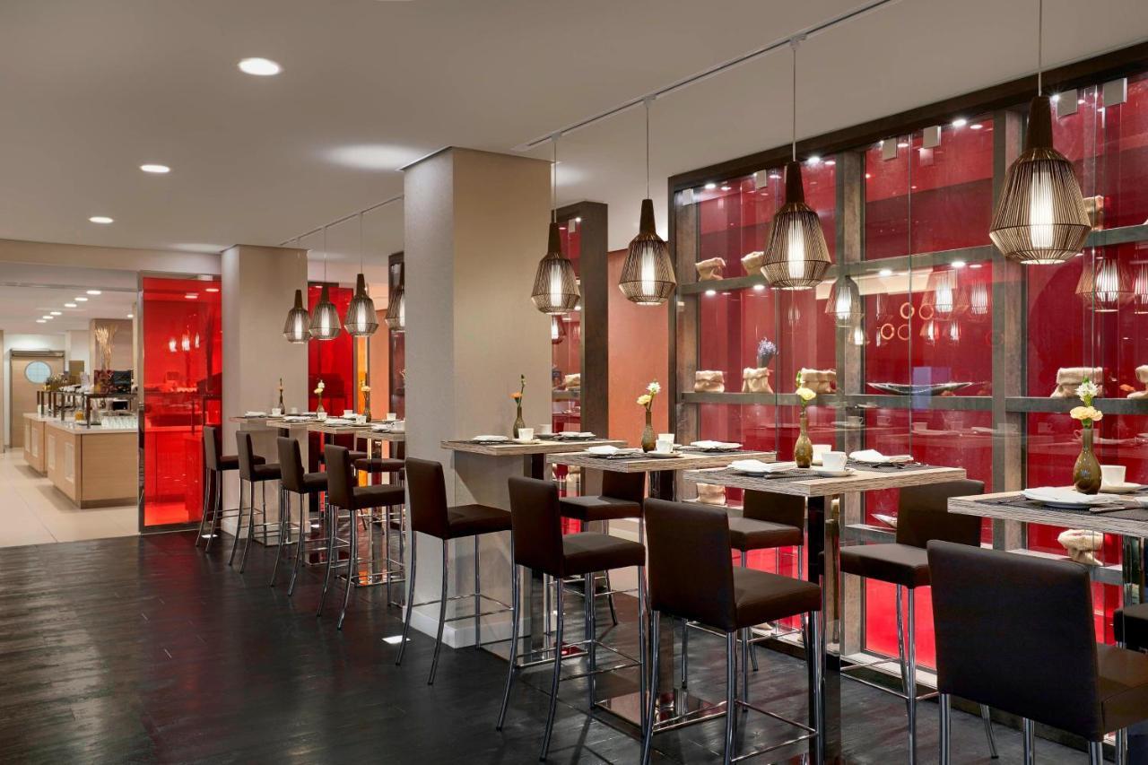מלון The Westin Hamburg Elbphilharmonie מראה חיצוני תמונה The photo shows a modern restaurant interior featuring a sleek, contemporary design. There are high tables with bar stools arranged along one side, illuminated by stylish hanging pendant lights. The color scheme includes warm tones, with red accents 